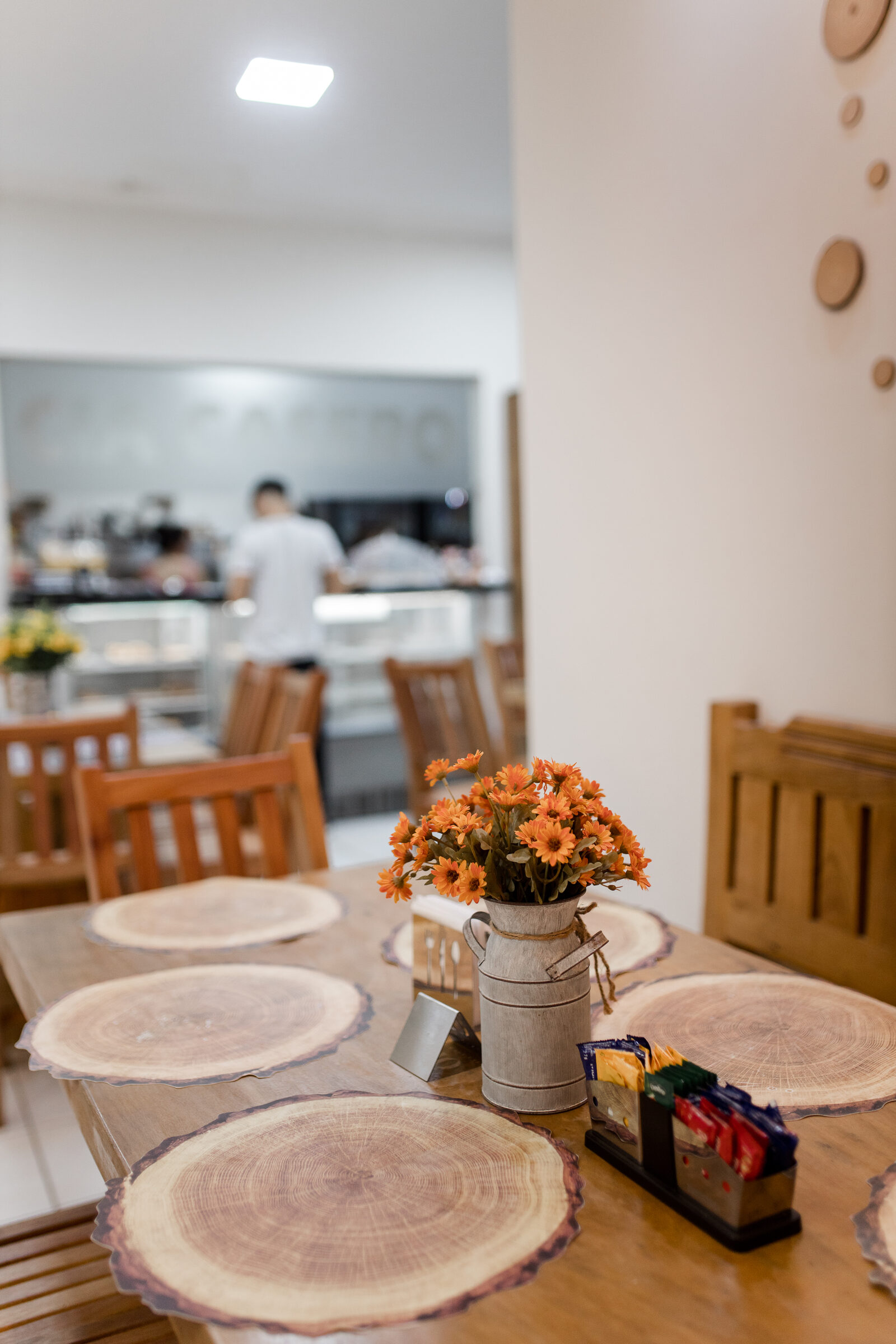 Mesa posta no salão da Cia Casero, com flores e sousplats de madeira